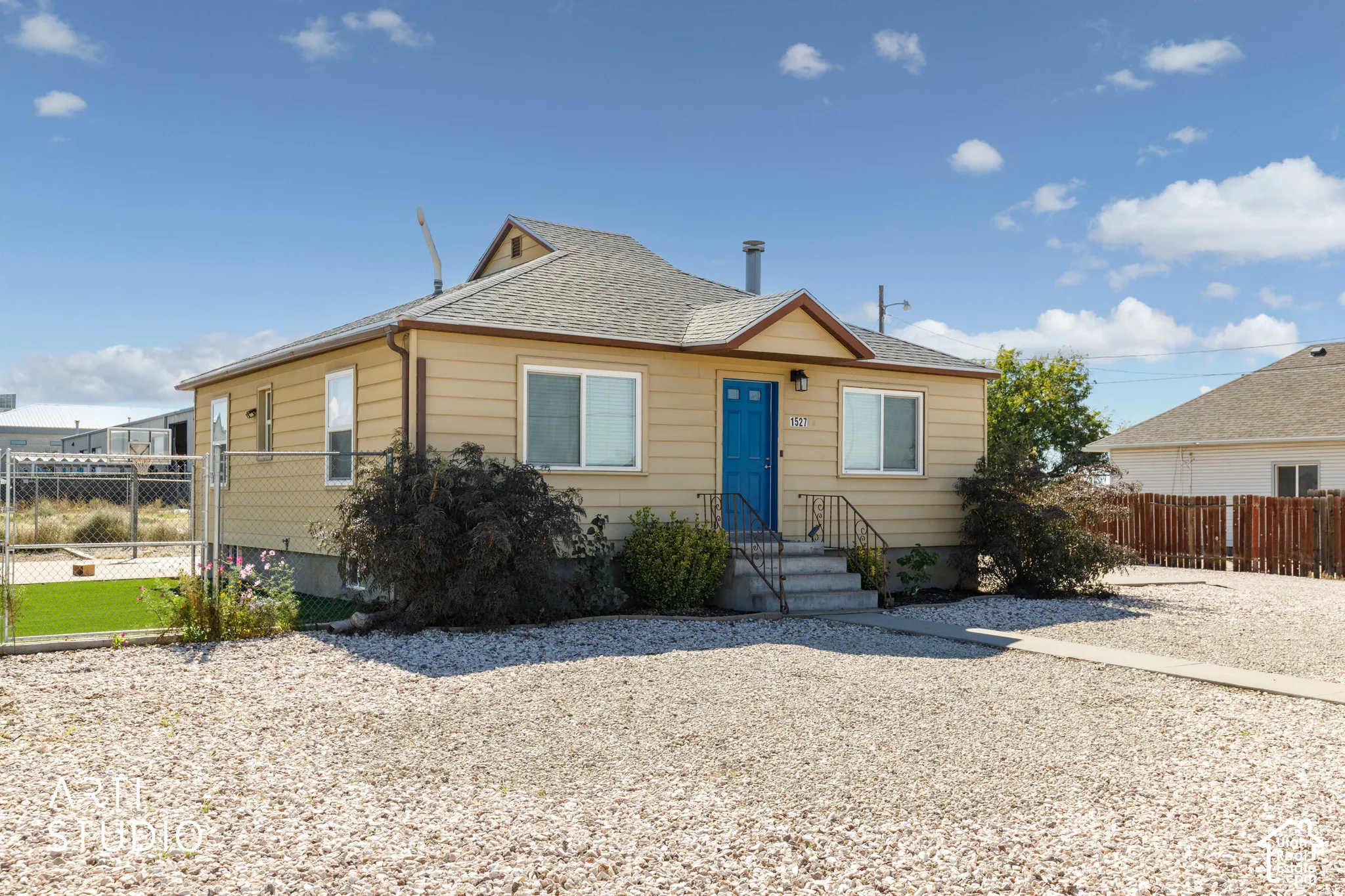 Single-story residence featuring light-colored siding, a blue entry door, and a gravel driveway