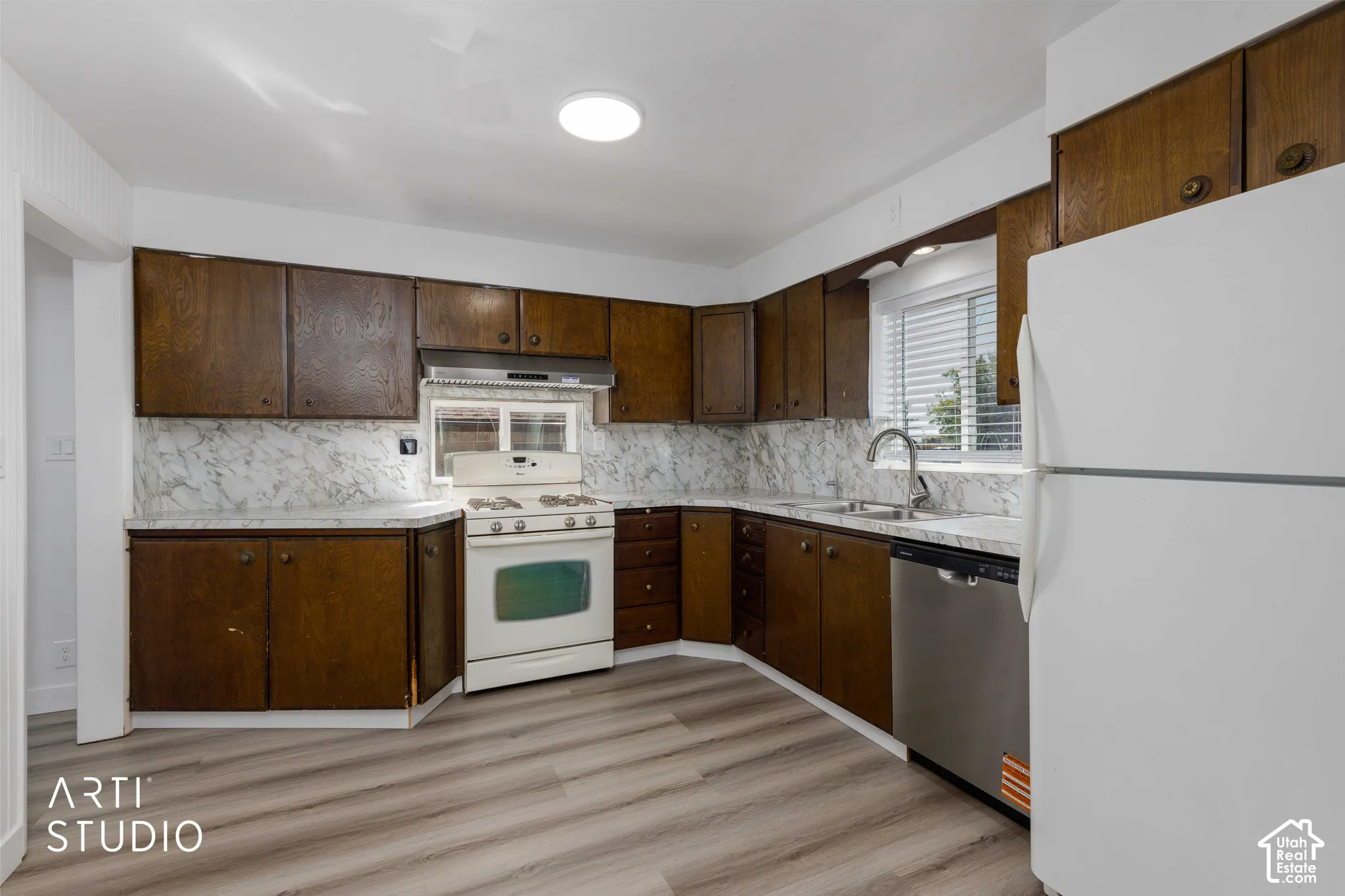 Wood-finish flooring, white walls, and dark wood cabinetry with brass hardware