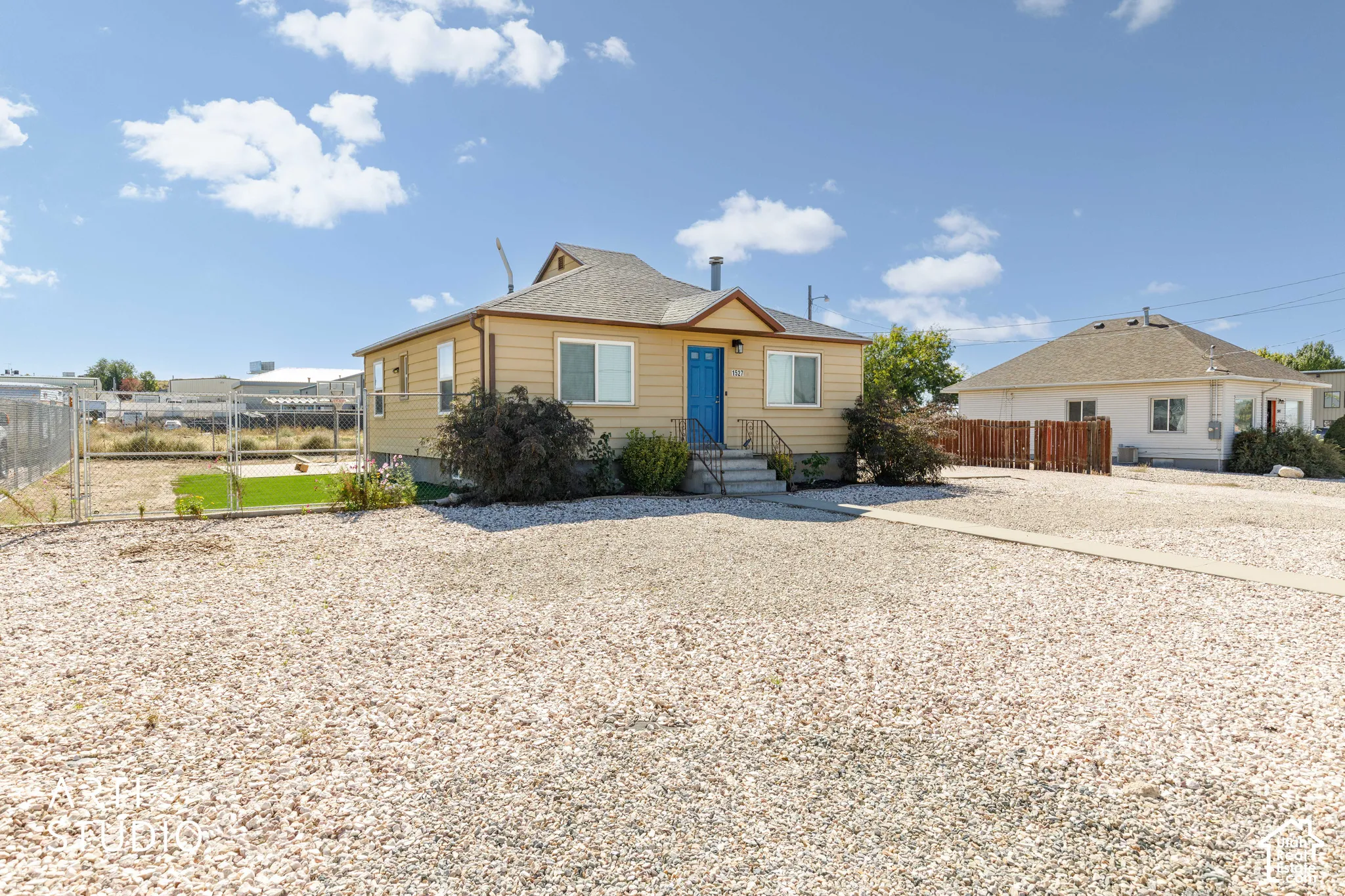 Single-story residence featuring a gravel front yard, a vibrant blue entry door, and a partially fenced side yard