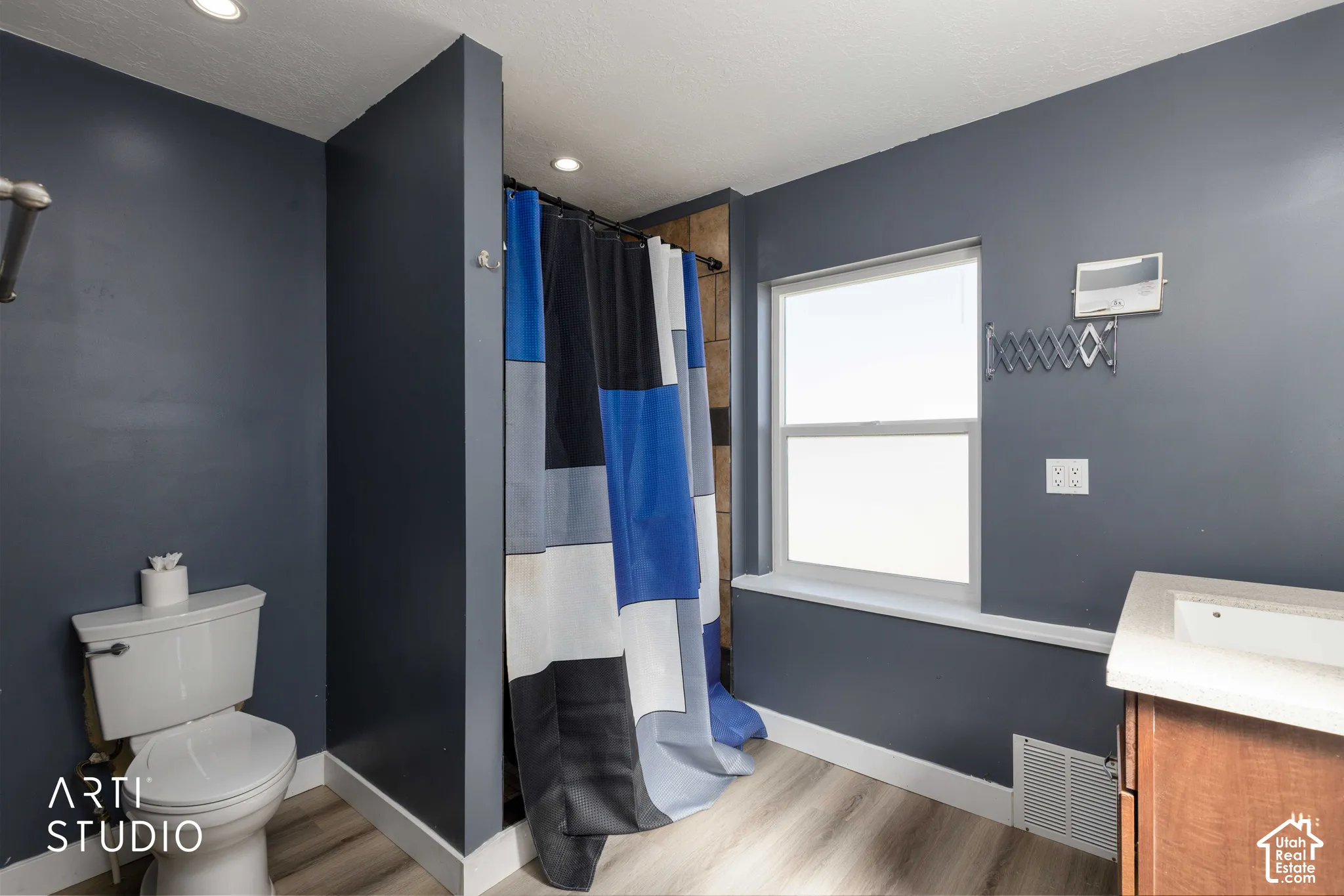 Modern bathroom featuring wood-finish flooring, a single window, recessed lighting, and a vanity with an integrated sink
