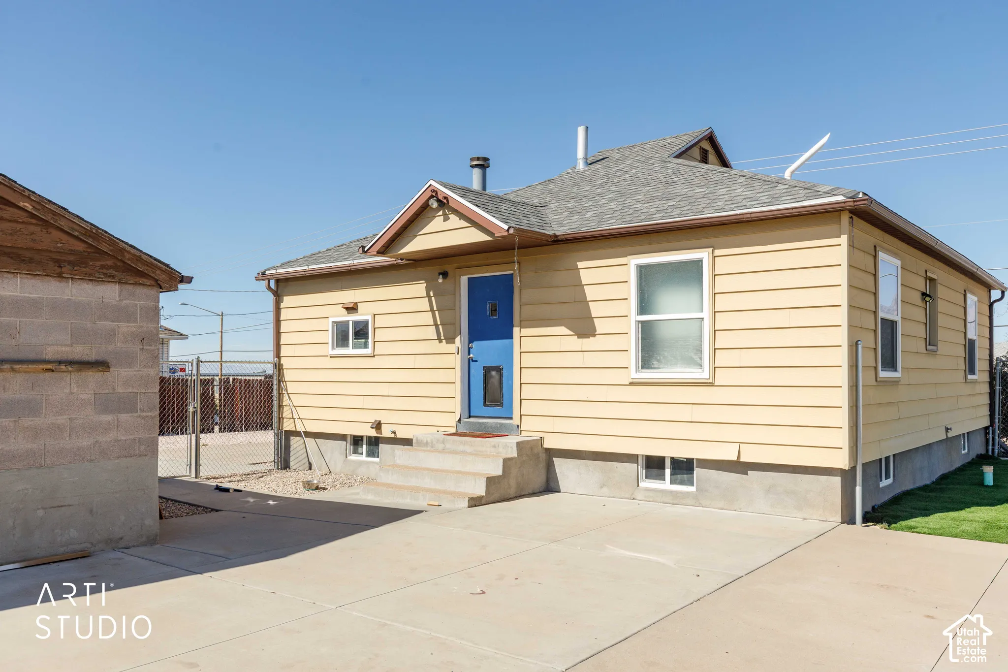Yellow siding exterior with a blue entry door, concrete steps, and a concrete driveway