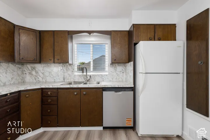 Wood-finish cabinetry, stainless steel dishwasher, dual basin sink, and wood-finish flooring