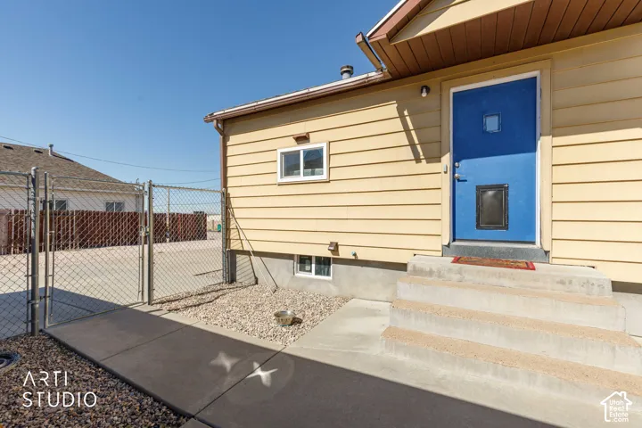 Entryway featuring a vibrant blue door, concrete steps, and horizontal siding