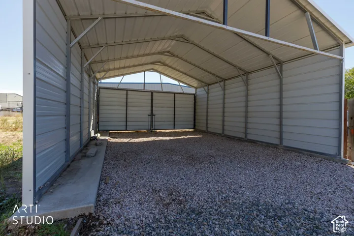Metal carport structure with a gravel floor, concrete base, and an additional enclosed storage area