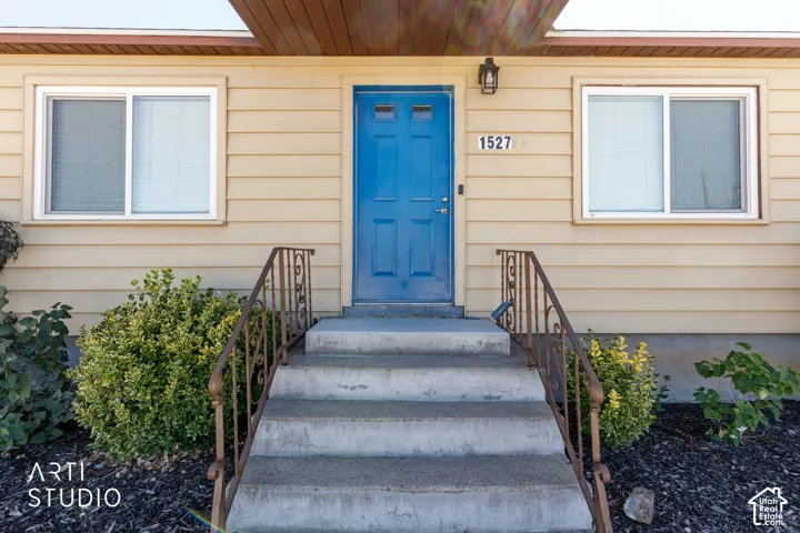 Exterior featuring horizontal siding, a vibrant blue entry door, and a concrete stairway with decorative metal railings