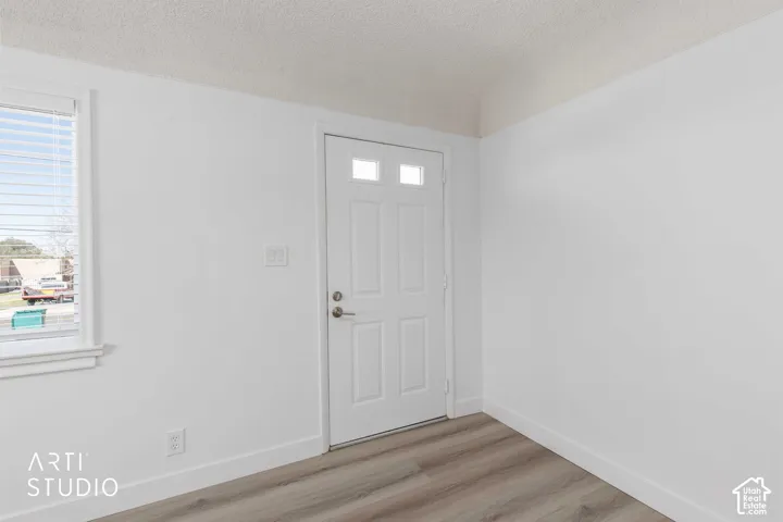 Entryway featuring a white paneled door with lites, wood-finish flooring, and a large window with blinds