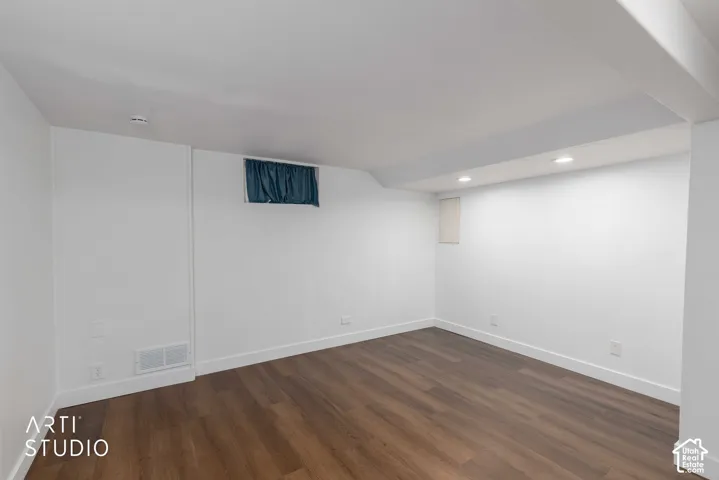 Recessed lighting illuminates the wood-finish flooring and bright white walls
