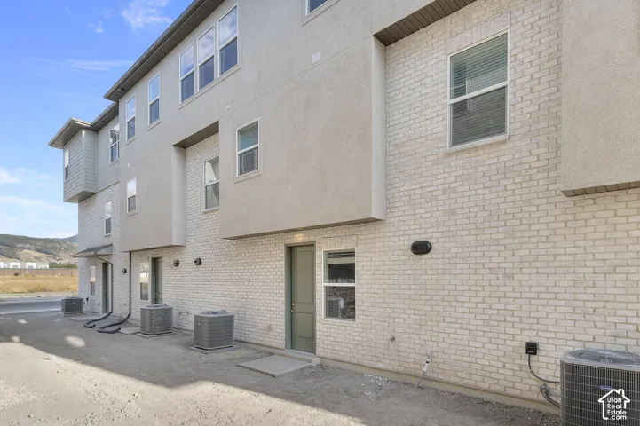 Multi-story exterior featuring a light-toned brick facade, stucco siding, and multiple windows