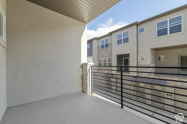Private balcony with a smooth concrete surface, stucco exterior wall, and contemporary metal railing