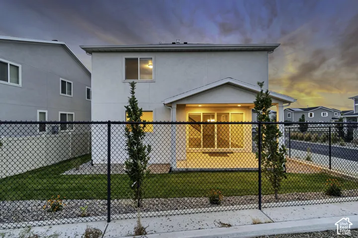 Rear exterior with a covered patio, chain link fencing, and a landscaped yard