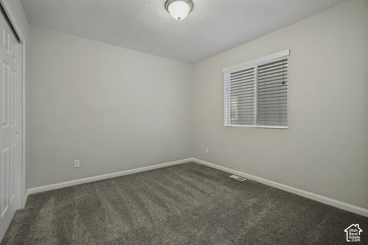 Wall-to-wall carpeting, single window with blinds, flush mount ceiling light, and bi-fold closet doors