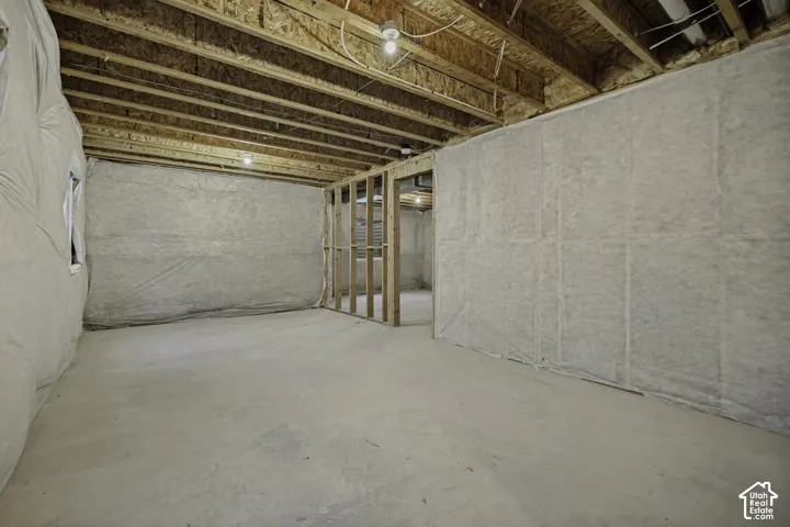 Unfinished lower level featuring exposed ceiling joists, concrete flooring, and insulated perimeter walls