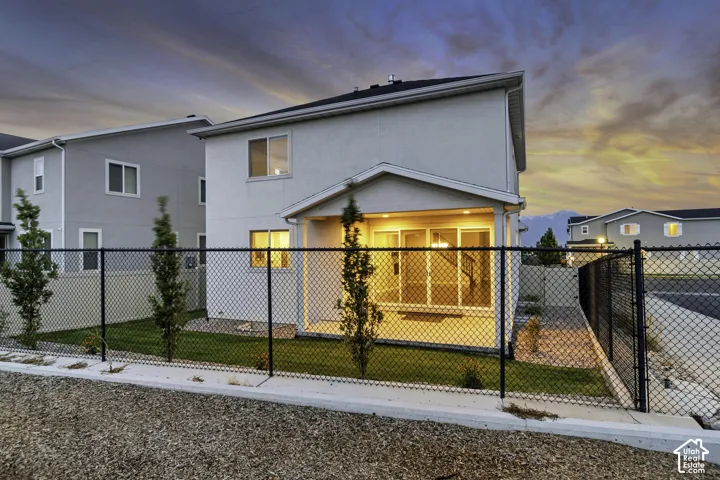 Rear exterior with a covered patio, chain-link fencing, and a manicured lawn