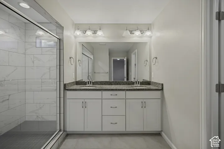 Dual vanity with granite countertop and undermount sinks, featuring a large mirror and wall-mounted light fixtures