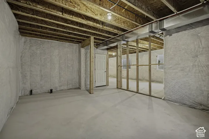 Unfinished basement featuring exposed joists, concrete flooring, and partial wood framing