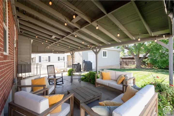 Covered patio with string lighting, concrete flooring, and direct access to a grassy yard