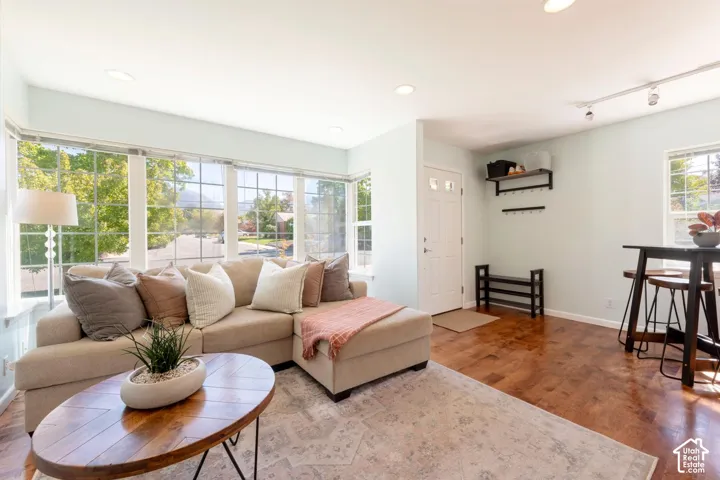 Expansive bay window, recessed ceiling lights, wood-finish flooring, entry door with decorative glass inserts, and track lighting