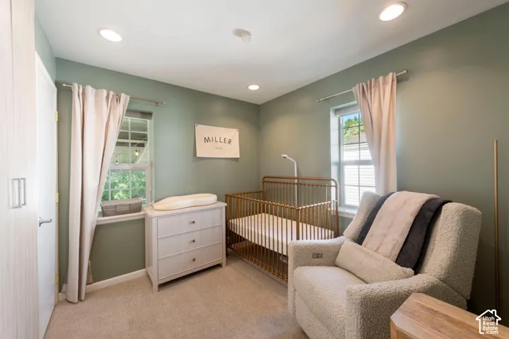 Recessed ceiling lighting, light-toned wall paint, two windows with natural light, and soft-toned carpeting
