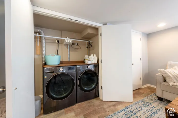 Dedicated laundry area with front-loading washer and dryer, wood-finish countertop, and built-in hanging rod