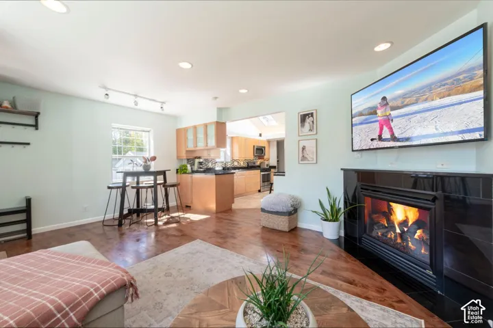 Wood-finish flooring throughout, recessed lighting, and a fireplace with a black tile surround