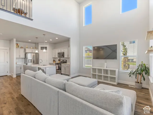 Soaring ceilings with upper-level windows, wood-finish flooring, and an open-concept layout