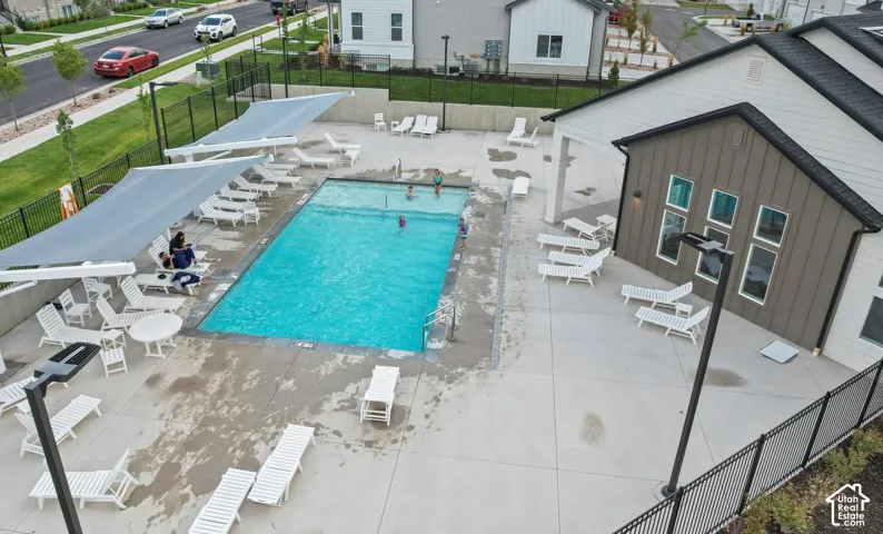 Outdoor swimming pool with concrete decking, shade structures, and a perimeter fence