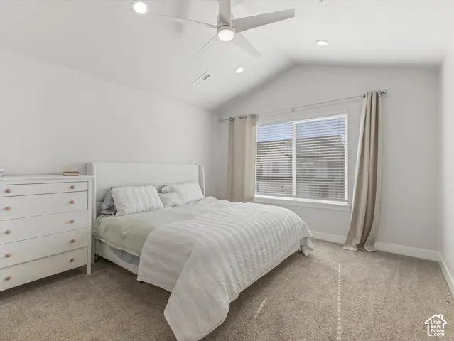 Primary Bedroom with ensuite . Vaulted ceiling with a ceiling fan, recessed lighting, carpet flooring, and a large window with blinds