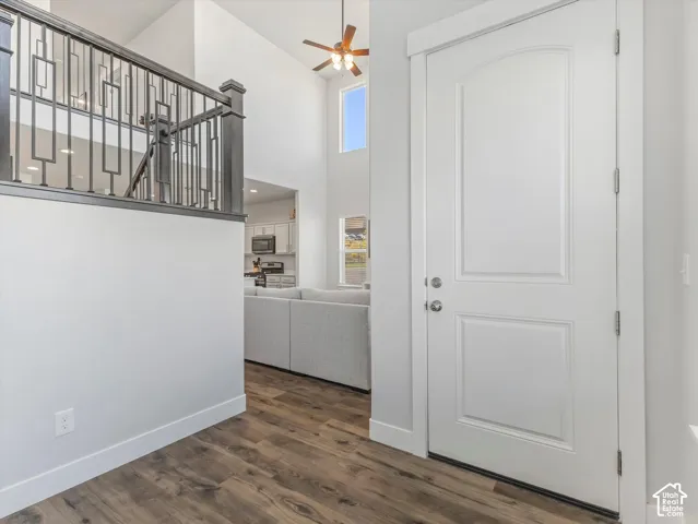 Two-story foyer with wood-finish flooring, a decorative metal stair railing, and a vaulted ceiling with an overhead fan