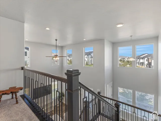 Multi-story interior with a dark wood-finish newel post and railings, black vertical balusters, wonderful views of valley and mountains.