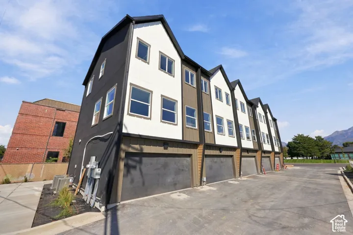 Contemporary townhome exterior featuring multi-toned siding, attached garages, and multiple window installations