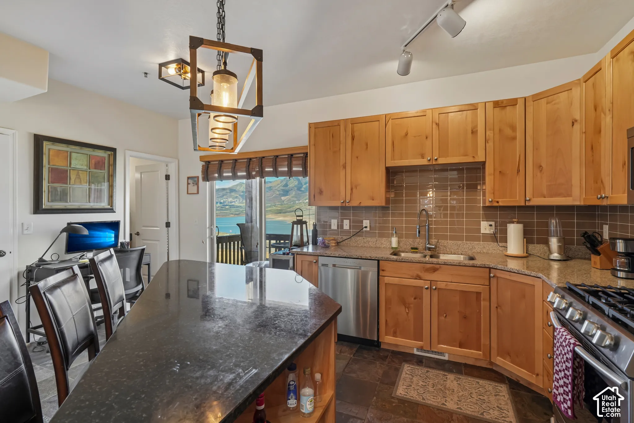 Kitchen featuring wood cabinets, stainless steel appliances, dark stone countertops, tile backsplash, and dark tile flooring