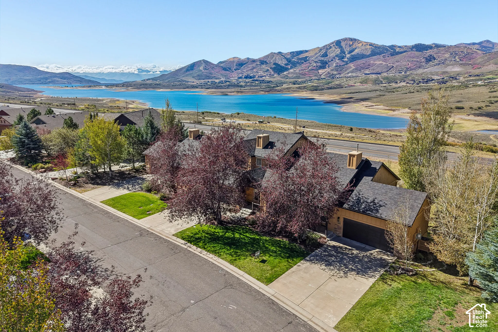Property featuring a paved driveway, attached garage, and mature landscaping