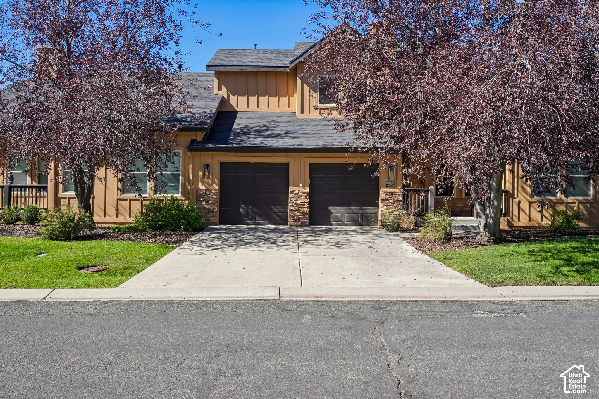 Two-story exterior with horizontal siding, stone accents, two attached garage bays, and a covered entry