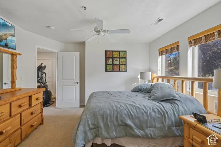 Carpeted room with a ceiling fan, two windows featuring wood blinds, and a white interior door