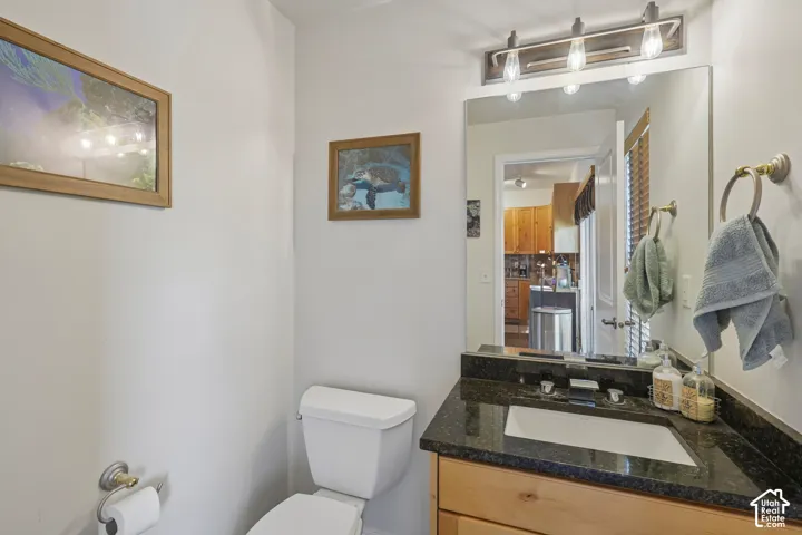Vanity with a dark countertop and undermount sink, illuminated by a multi-bulb light fixture