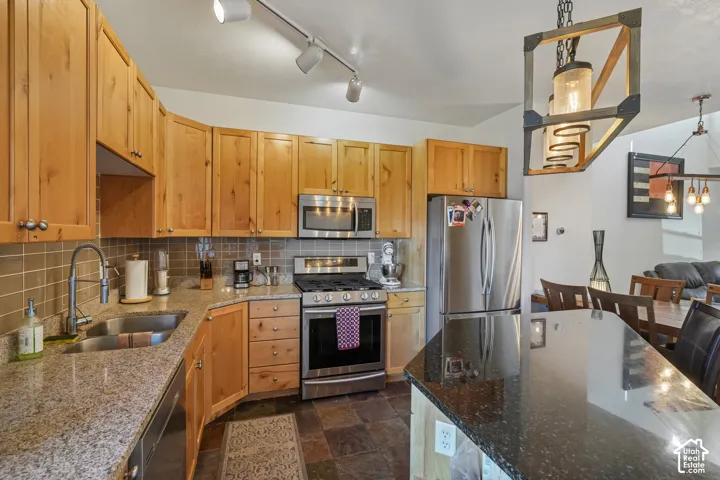Kitchen featuring wood cabinetry, stainless steel appliances, granite countertops, and tiled flooring