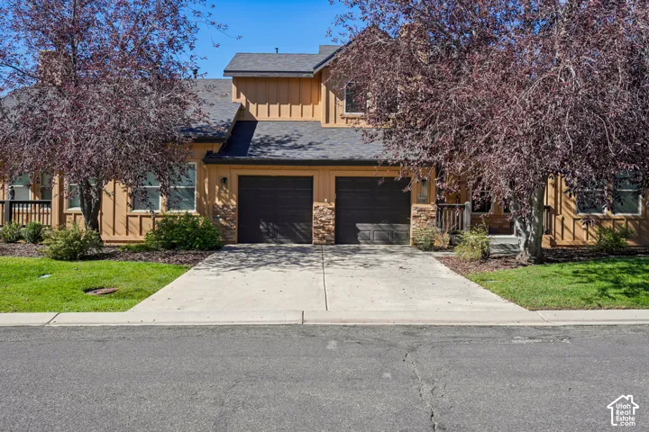 Two-story exterior with horizontal siding, stone accents, two attached garage bays, and a covered entry