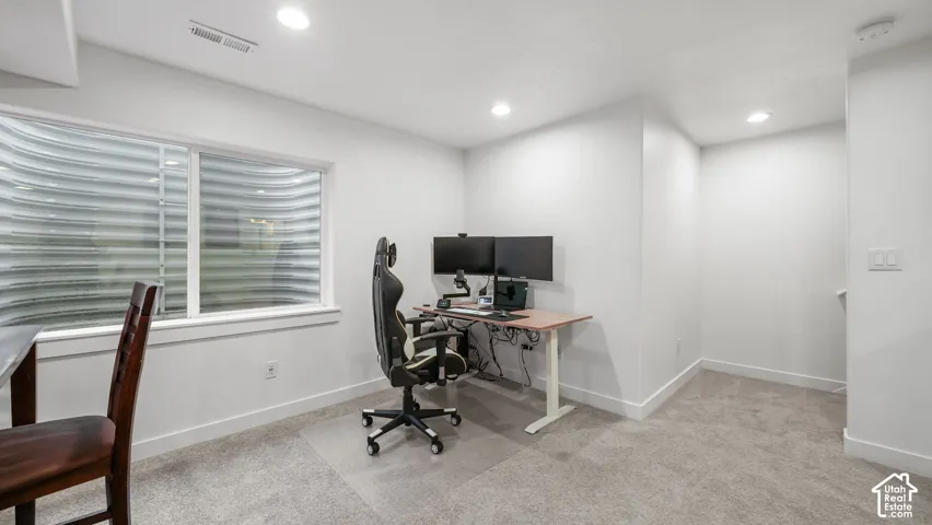 Recessed lighting illuminating the room with light gray carpeting and white walls