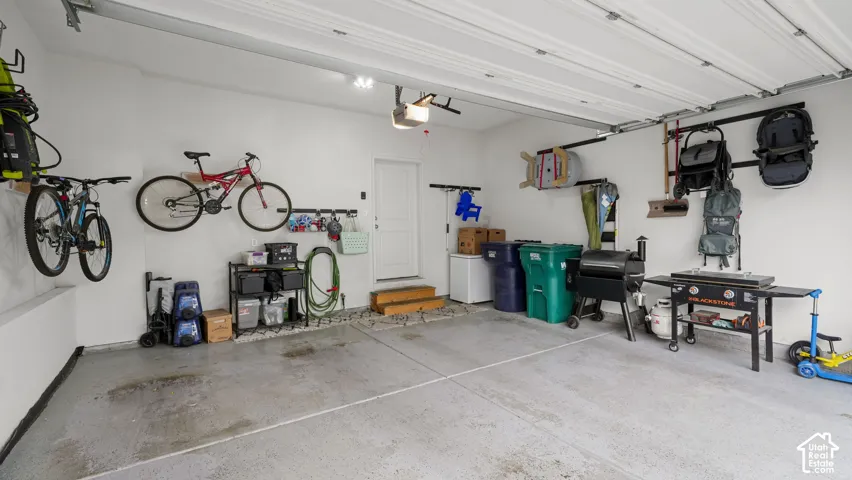 Spacious garage featuring a concrete floor, overhead garage door, and a white entry door