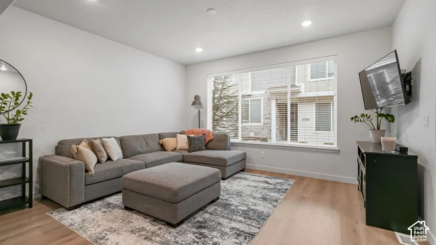 Recessed lighting, large picture window with blinds, wood-finish flooring, and light-toned walls