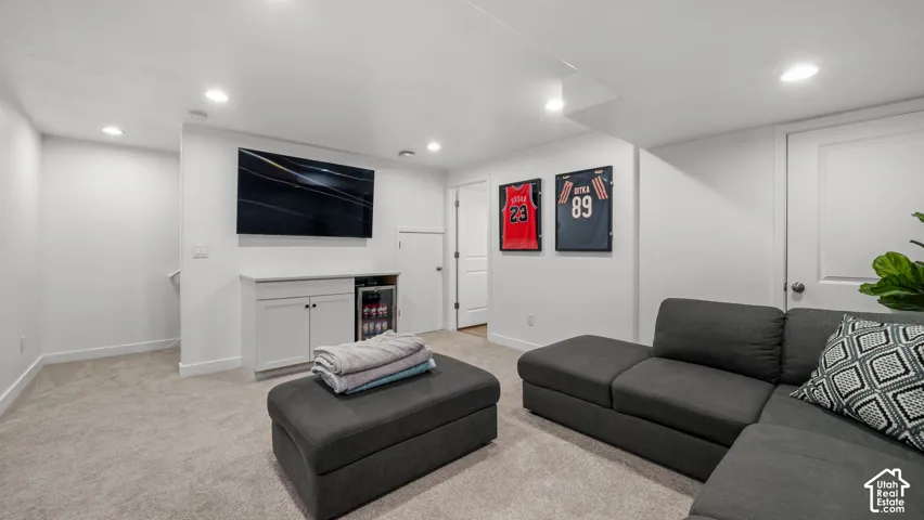 Built-in cabinetry with counter space, integrated beverage cooler, recessed lighting, and neutral carpet flooring