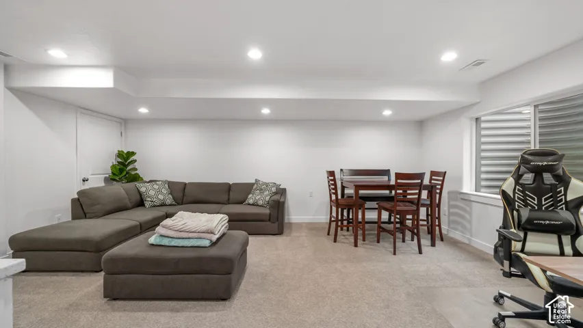 Recessed lighting illuminates the open-concept space, featuring neutral carpet flooring and white walls