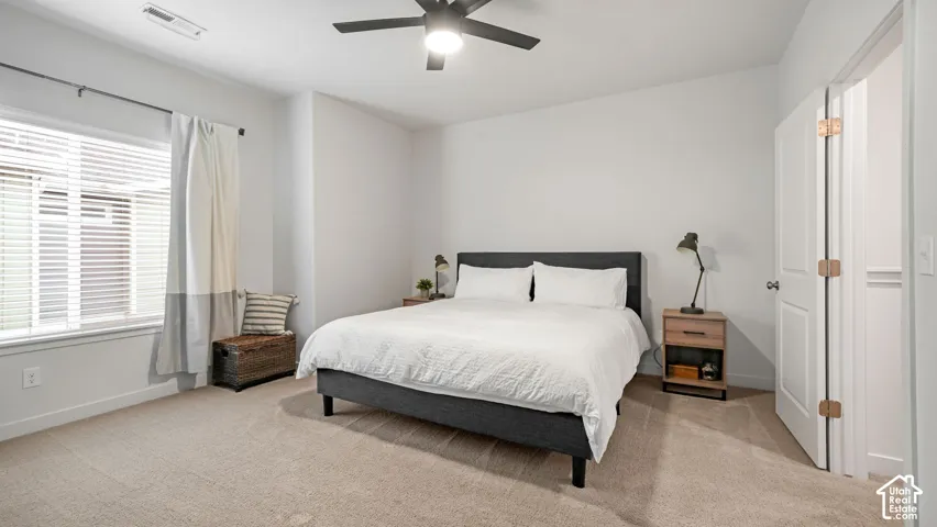 Wall-to-wall carpeting in a neutral tone, ceiling fan with integrated lighting, window with horizontal blinds, and a paneled interior door