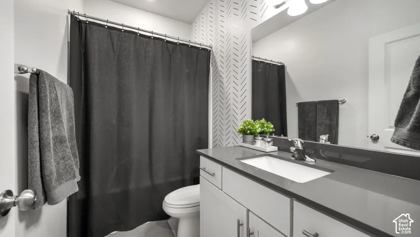 Vanity with integrated sink and chrome faucet, under-counter cabinetry, full-width mirror, and patterned accent wall
