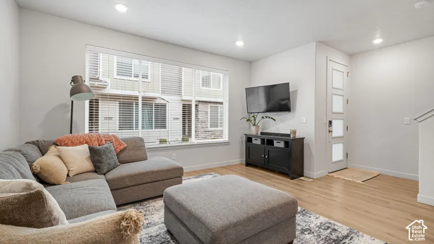Recessed lighting, wood-finish flooring, and a large window with horizontal blinds
