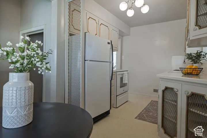 Kitchen featuring white cabinetry, a white refrigerator, and a white electric range