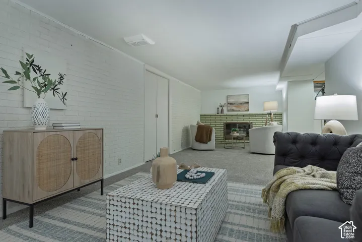 Brick accent wall, carpeted flooring, fireplace with light tile