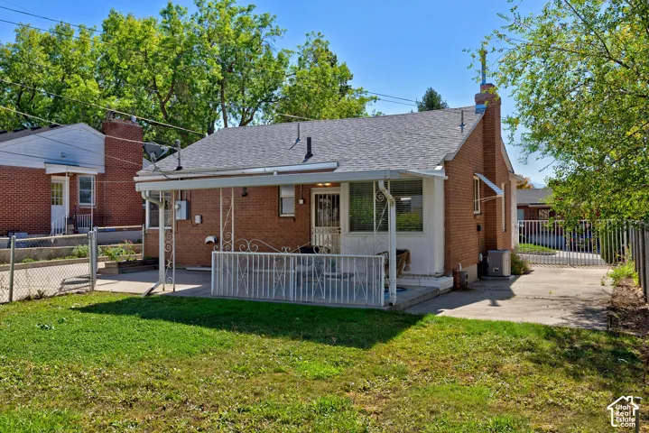 Brick exterior with an asphalt shingle roof, a covered patio featuring decorative metalwork, and a concrete driveway