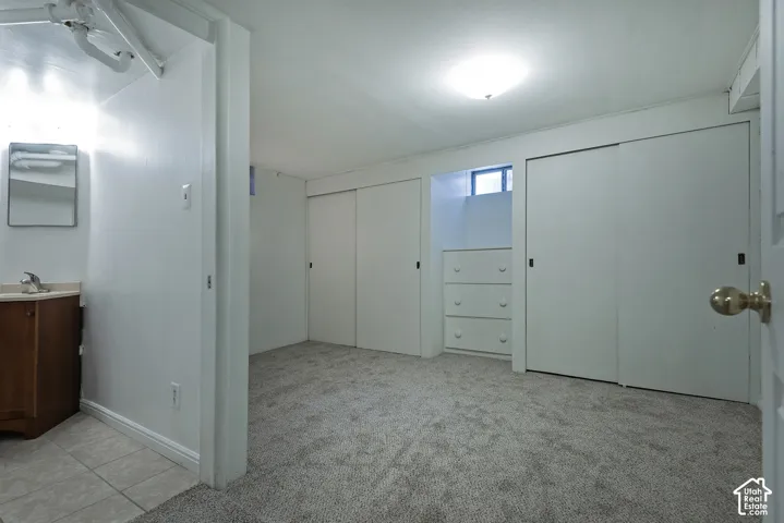 Bedroom with dual closets, built-in shelving and drawer storage, carpeted flooring, and natural light