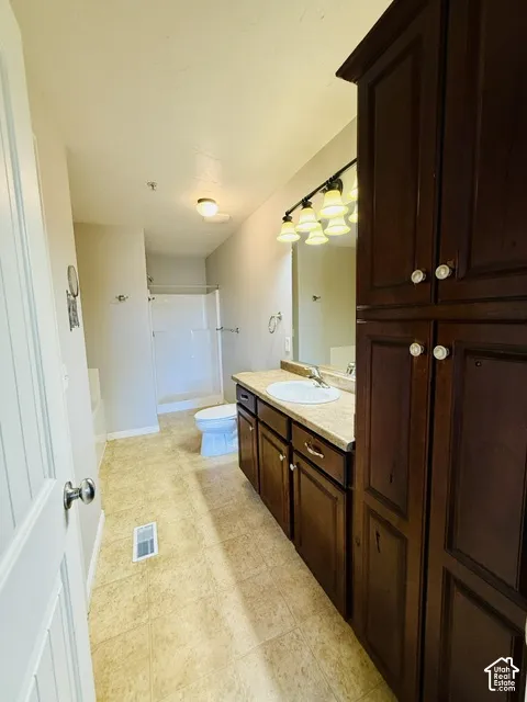 Full vanity with integrated sink, dark wood-finish cabinetry, and overhead sconce lighting